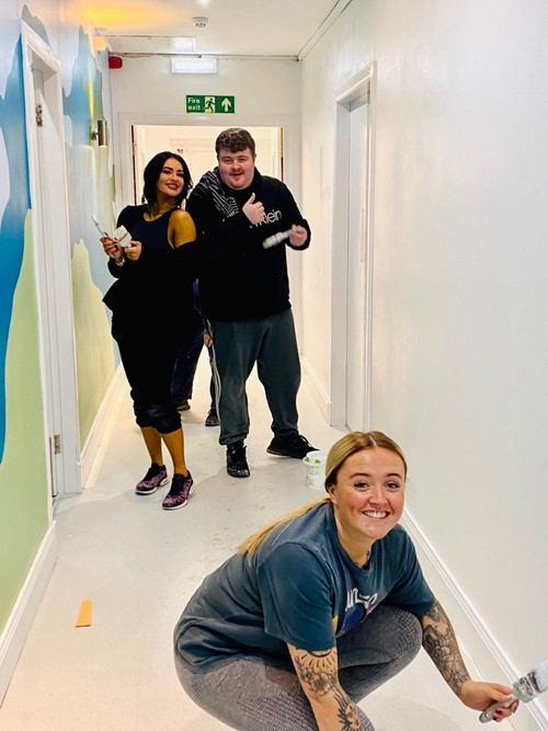 Three volunteers painting a corridor with rollers