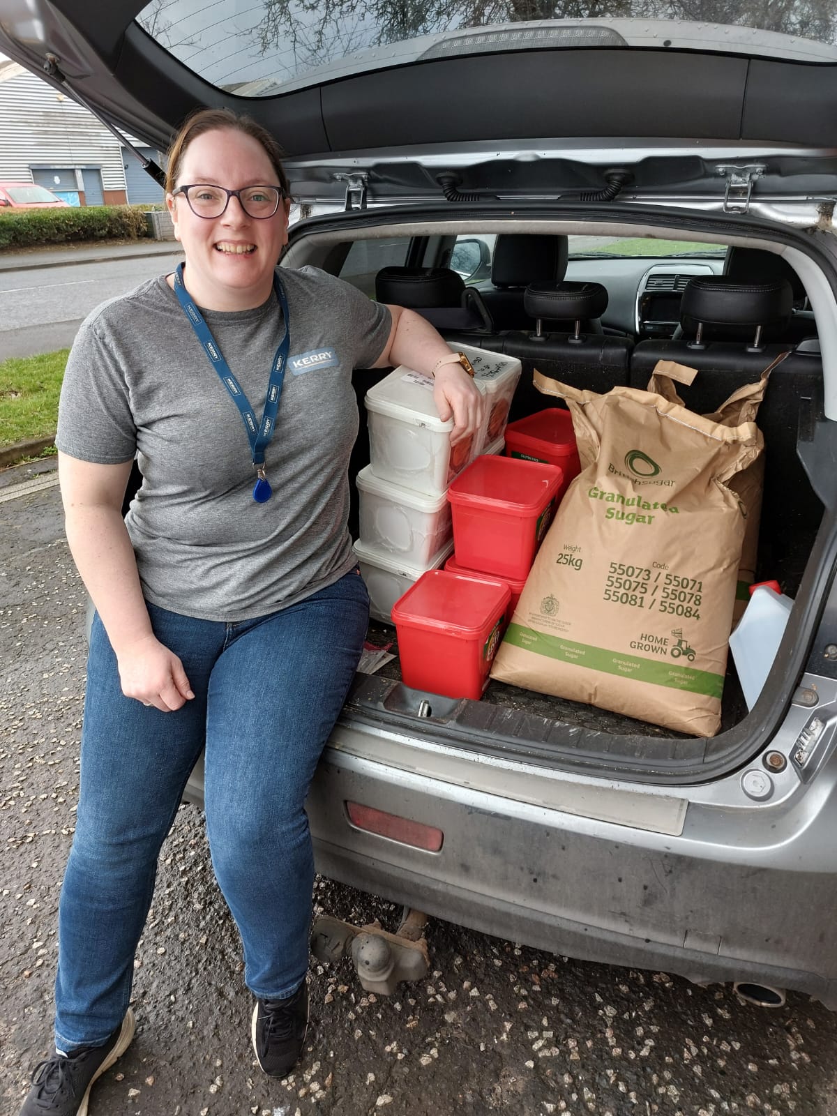Volunteer beside a car boot filled with donated catering ingredients