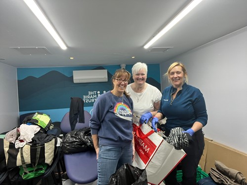 Three volunteers sorting bags of donated clothing