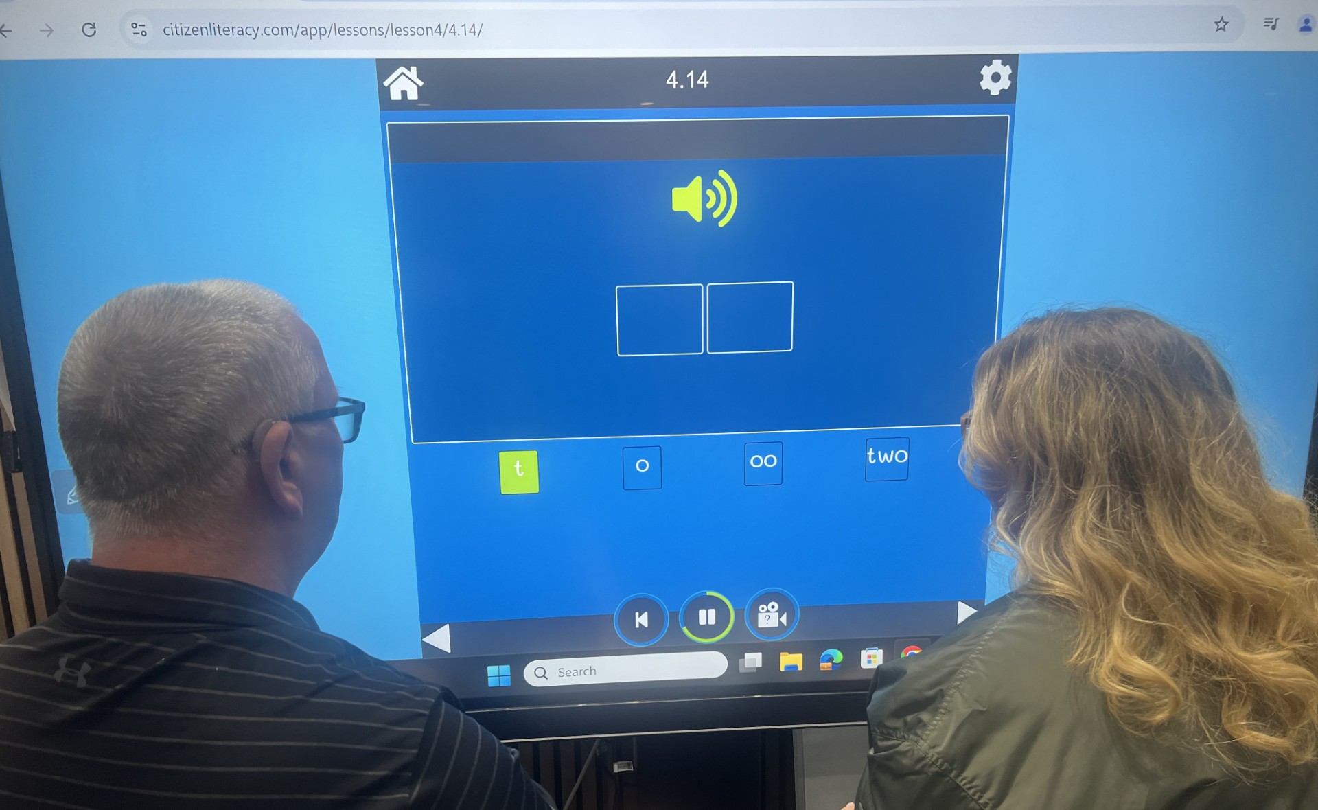 Two people using the Citizen Literacy platform on a large touchscreen