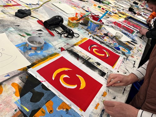 Screen printing in progress on a table covered in paint