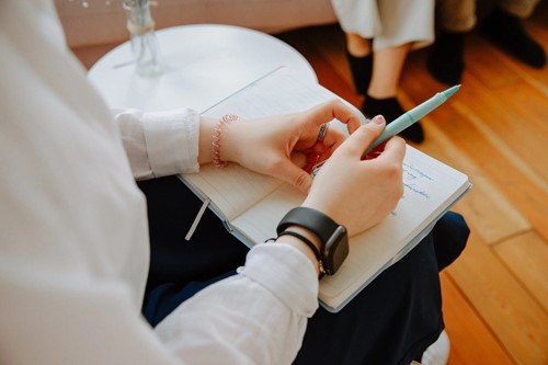 A learner writing notes in a notebook during a course session