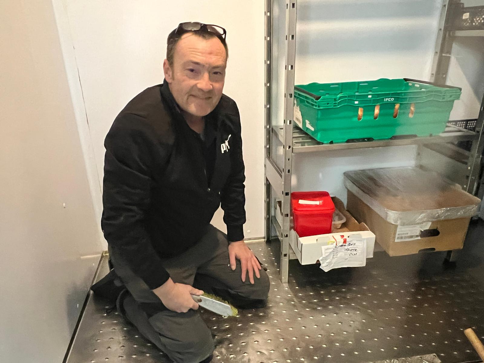 A volunteer cleaning shelving in The Marie Trust's kitchen store