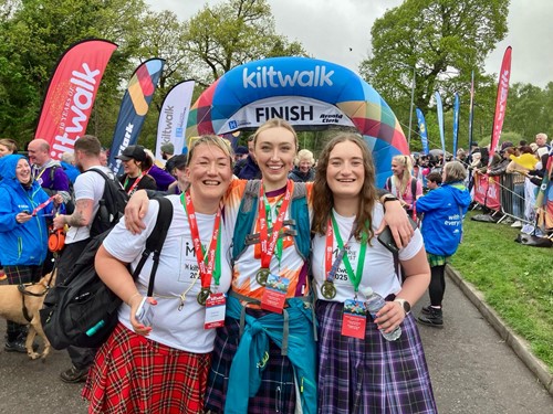 Three Team Marie Trust walkers with medals at the Kiltwalk finish line