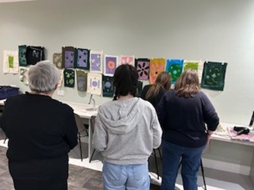 People looking at artwork displayed along a wall in the education room