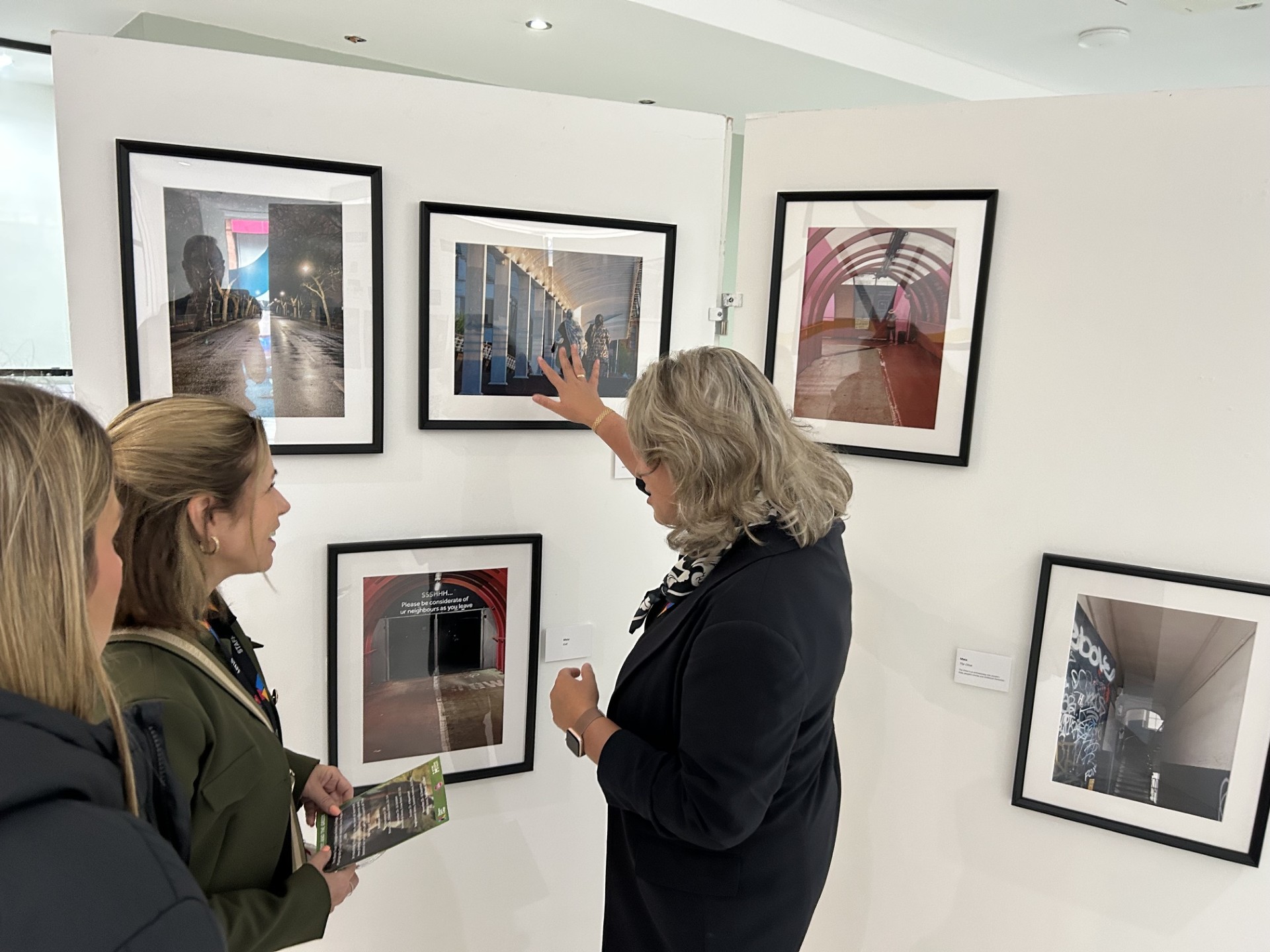 Visitors viewing framed photographs at a learner exhibition