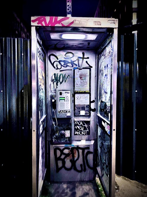 The inside of a graffiti-covered telephone box lit at night