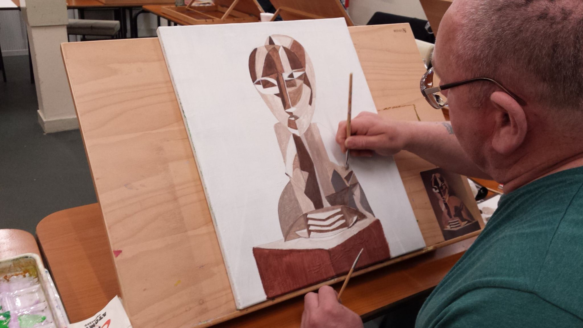 A learner painting a portrait on canvas in an art class