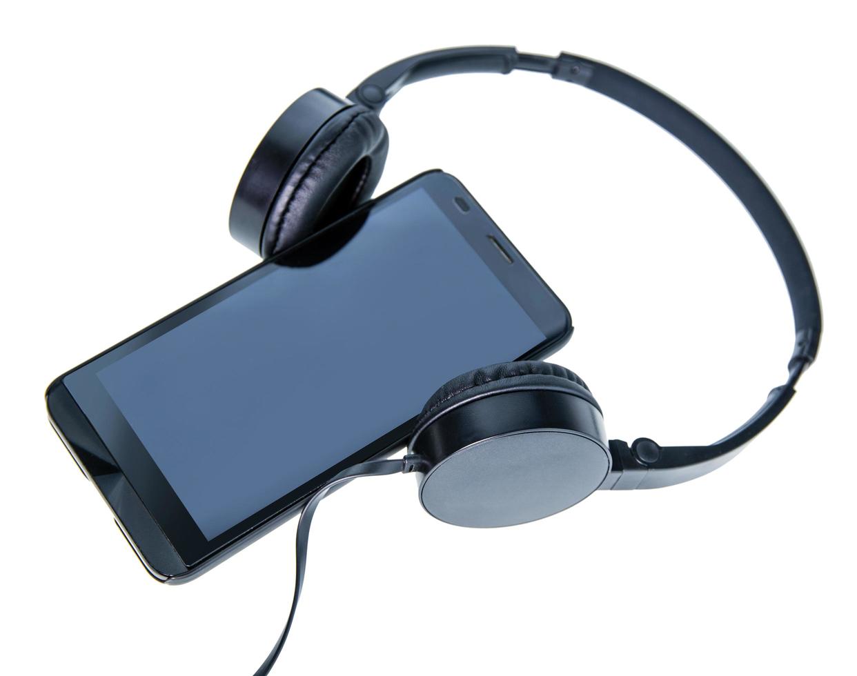A smartphone lying beside a pair of black headphones